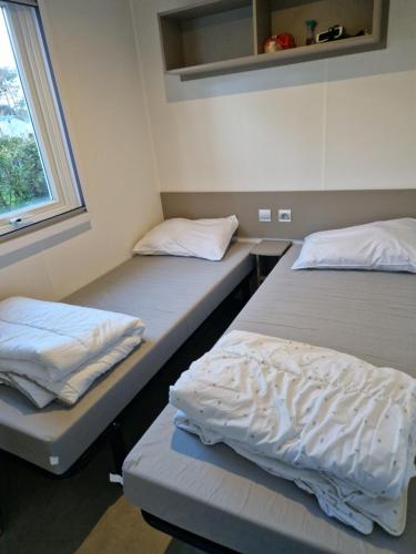 2 camas individuales en una habitación con ventana en Mobil home 108 Siblu La Pignade Fun pass non inclus, en La Tremblade