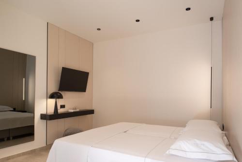 a white bedroom with a bed and a tv at Cueva Villas, with Pool, SeaViews & close to Sea, By ThinkVilla in Balíon