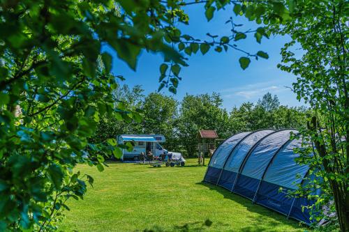 a blue tent in a field with a bus at Mini Camping Drentse Monden in Nieuw-Weerdinge