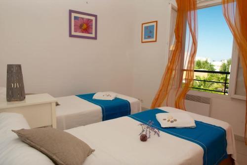 Cette chambre comprend 3 lits et une fenêtre avec vue. dans l'établissement Villa St louis à 50m de la mer+6 velos +Piscine+climatisation, à Sète