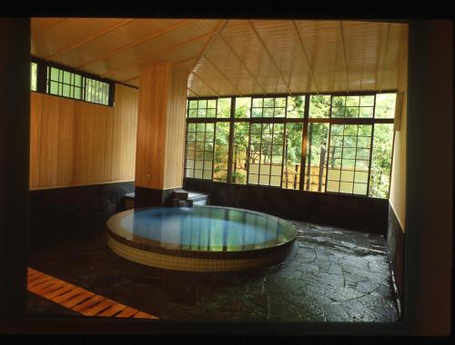 a large room with a large tub in a room with windows at Sansuien in Yamaguchi