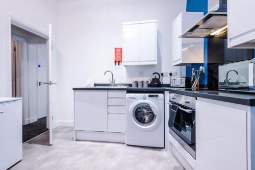 Una cocina blanca con lavadora y secadora. en Charming Apartments - Rocky Ln Chambers Flat 4, en Liverpool