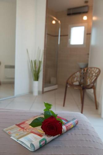 une rose assise sur un livre sur un lit dans l'établissement Villa St louis à 50m de la mer+6 velos +Piscine+climatisation, à Sète