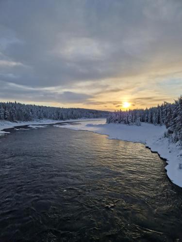 Jock的住宿－Överkalix Kalixalven Lodge Jockfall，雪中河流,太阳在背后