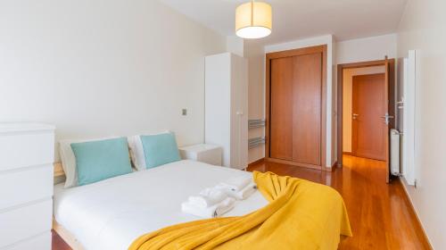 um quarto com uma cama branca com um cobertor amarelo em Magnificent Matosinhos Sul Apartment by Unique Hosts em Matosinhos