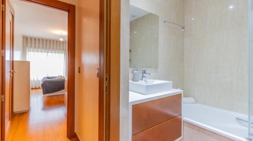 uma casa de banho com um lavatório, um espelho e uma banheira em Magnificent Matosinhos Sul Apartment by Unique Hosts em Matosinhos
