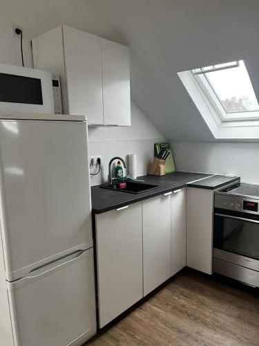 eine Küche mit weißen Schränken und einem weißen Kühlschrank in der Unterkunft Studio Apartment Koblenz in Koblenz