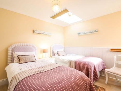 Un dormitorio con dos camas y una silla. en Bwthyn Yr Hafod, en Benllech