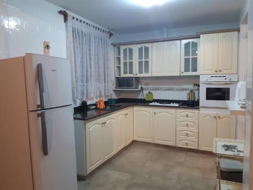 uma cozinha com armários brancos e um frigorífico branco em ENCANTOS DE MENDOZA Apartments em Mendoza