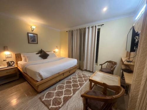 a bedroom with a bed and a desk and a television at HighField Villa in Kanatal