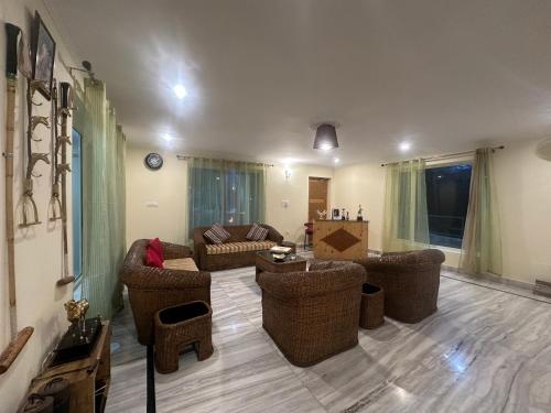 a living room with a couch and chairs and a table at HighField Villa in Kanatal