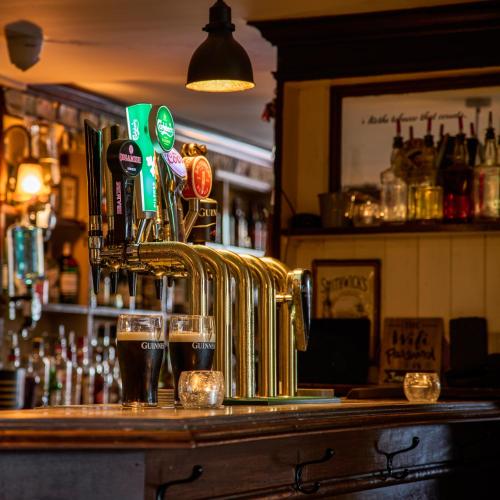 a bar with two glasses of beer on a counter at Castlemartyr Resort Hotel in Castlemartyr
