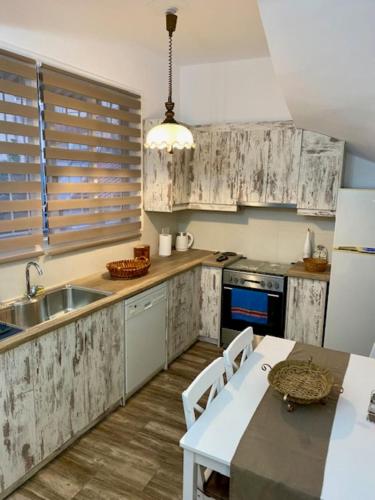 a kitchen with white cabinets and a sink and a table at Zante Town Apartment in Zakynthos