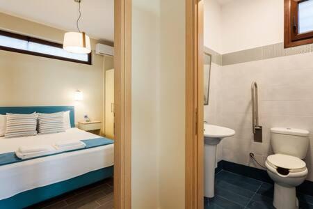 y baño con cama, aseo y lavamanos. en Seaside Summer Bliss - Aurora Luxury Pool Paradise, en Petalidi