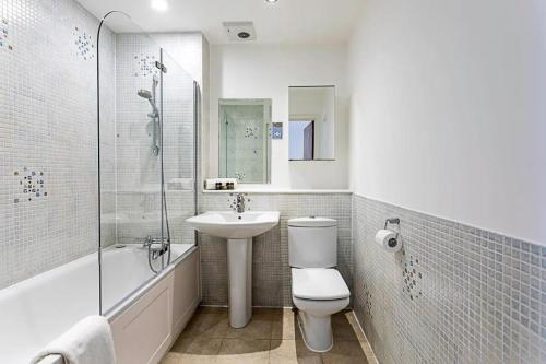 a bathroom with a toilet and a sink and a bath tub at 2BR, Gated parking, 50" TV, Nespresso machine in London