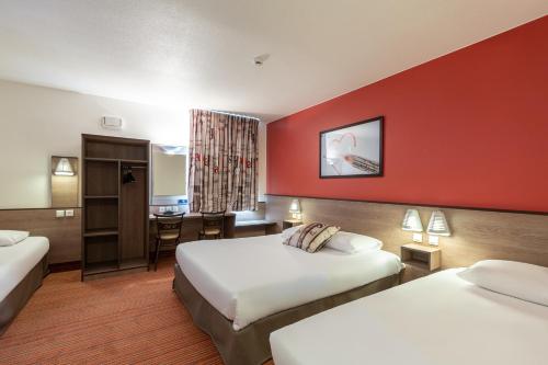 バイー・ロマンヴィリエにあるエース オテル パリ マルヌ・ラ・ヴァレのベッド2台とデスクが備わるホテルルームです。