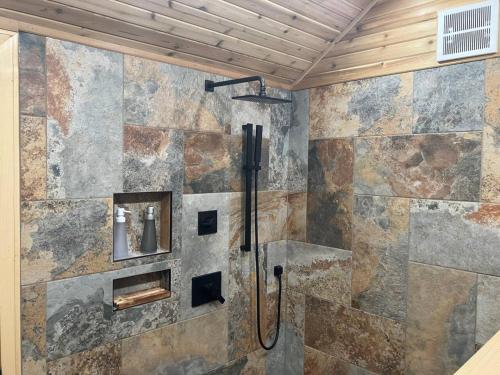 y baño con ducha y pared de piedra. en Two Lakes Guesthouse, en Seward