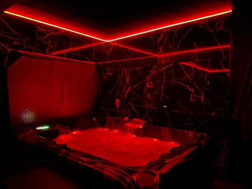 a dark room with a hot tub with red lights at Love Room Passion in Saint-Hilaire-de-Talmont