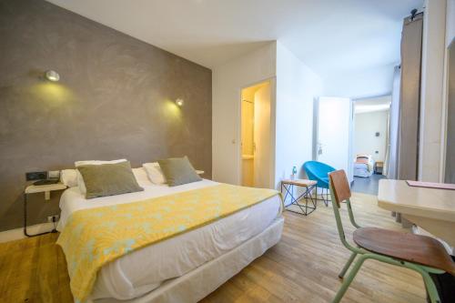 a bedroom with a large bed and a desk and a table at Hotel Le Clocher in Ars-en-Ré