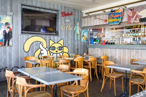 a restaurant with tables and chairs and a wall with graffiti at Hotel Le Clocher in Ars-en-Ré