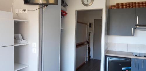 une cuisine avec des placards blancs et une horloge murale dans l'établissement Studio-cabine Station de ski Super Lioran, à Laveissière