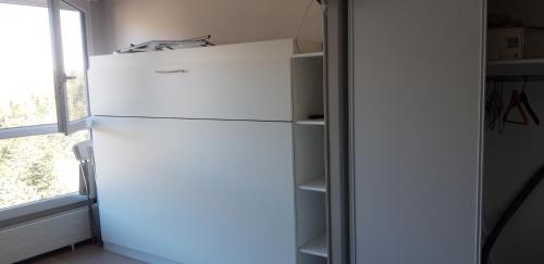 a white refrigerator in a room with a window at Studio-cabine Station de ski Super Lioran in Laveissière