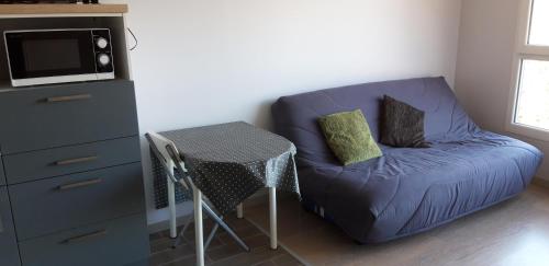 un salon avec un canapé bleu et une table dans l'établissement Studio-cabine Station de ski Super Lioran, à Laveissière