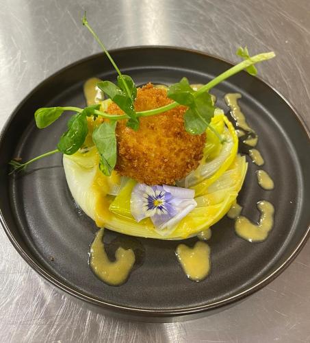 une assiette avec un plat sur une table dans l'établissement Hôtel Le Dormeur du Val, à Charleville-Mézières