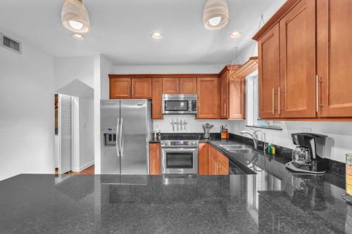 a kitchen with wooden cabinets and a stainless steel refrigerator at Center Grove - Lush & Spacious & New - 3 Bedrooms in Miami