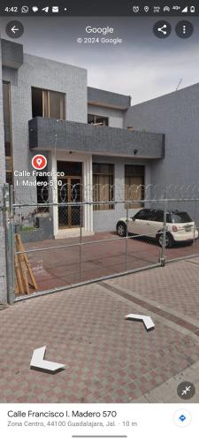 a building with a car parked in front of a fence at Habitación privada en casa de huespedes in Guadalajara