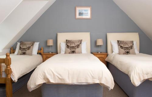 een slaapkamer op zolder met 2 bedden en 2 lampen bij Stationmasters Lodge in Stromeferry