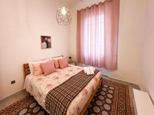 Un dormitorio con una cama con almohadas rosas y una ventana en La Casa di Eli en Pisa