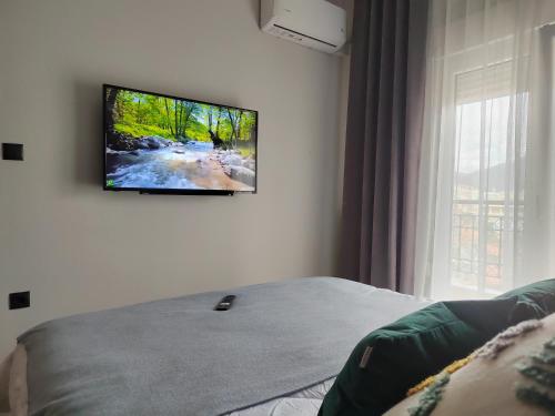 TV de pantalla plana colgada en la pared de un dormitorio en North Key - Cozy apartment with a beautiful view, en Xanthi