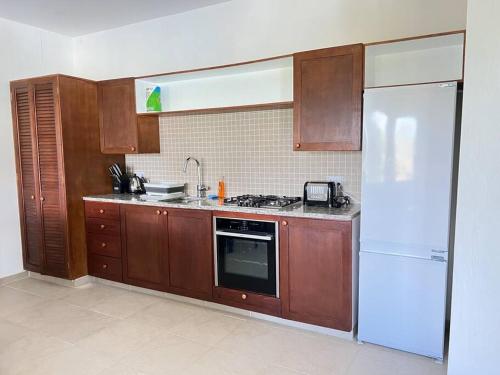 - une cuisine avec des placards en bois et un réfrigérateur blanc dans l'établissement Aruanda Apartment - perfect get-away for two at the top of Bequia, à Union