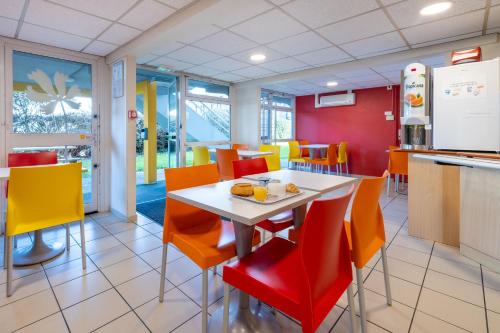 a dining room with a white table and orange chairs at Premiere Classe Angers Beaucouzé in Beaucouzé