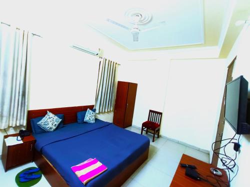 a bedroom with a blue bed and a tv at Hotel S-14 in Jaipur