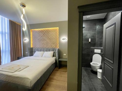 a bedroom with a bed and a bathroom with a toilet at GRAND JNK Boutique Hotel in Kukës