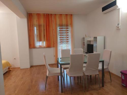 a dining room with a table and white chairs at sunny apartments near the sandy beach in Omiš