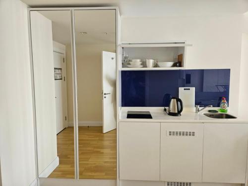 a kitchen with white cabinets and a blue wall at Orbi apartament in Batumi