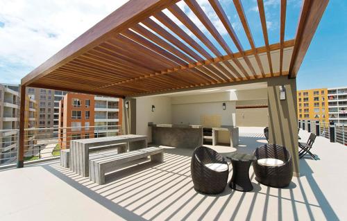 pérgola de madera en una terraza con sillas y mesa en Bonito departamento VIP estreno en Condominio en Lima