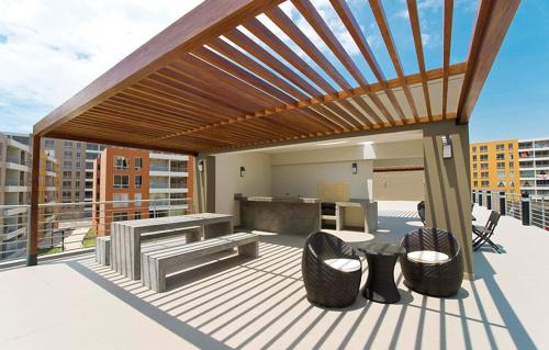 eine hölzerne Pergola auf einer Terrasse mit Stühlen und einem Tisch in der Unterkunft Bonito departamento VIP estreno en Condominio in Lima