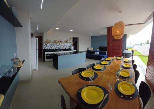 a long wooden table with yellow plates on it in a living room at Casa em condomínio de Cotovelo c/ vista para o mar in Parnamirim