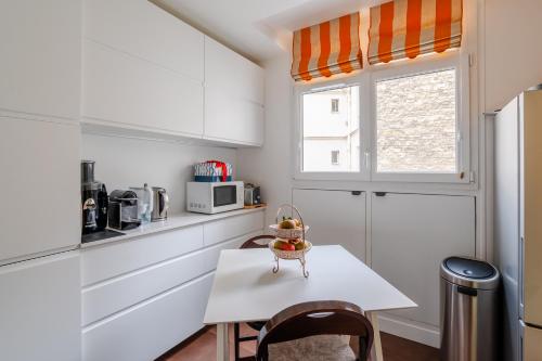 une cuisine blanche avec une table et une fenêtre dans l'établissement Veeve - Culture and Colour, à Paris