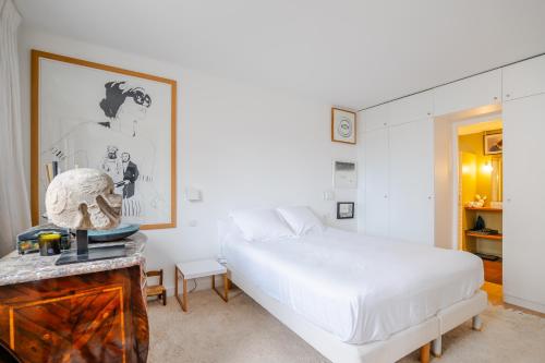 une chambre blanche avec un lit et une table dans l'établissement Veeve - Culture and Colour, à Paris