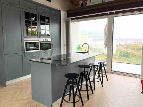 a kitchen with a island with bar stools and a large window at Casa Albuerne in Gijón