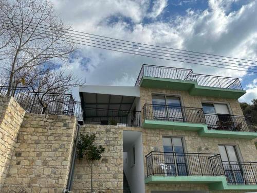 un edificio con balcones en la parte superior de una pared de piedra en Chambous house, en Kelokedhara