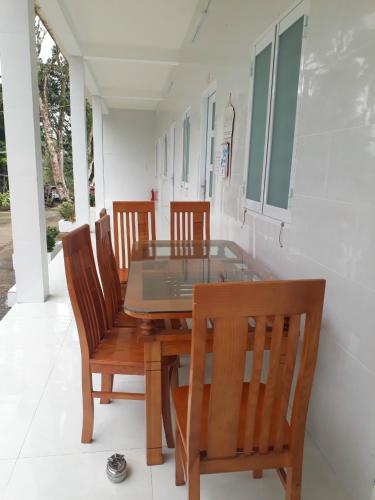 a dining room table with four chairs and a glass table at Nhà Nghỉ Tốt Hơn in Phu Quoc