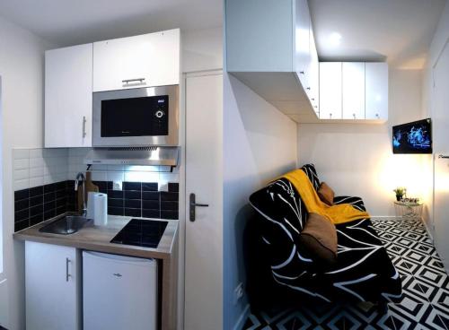 une personne assise sur un canapé dans une petite cuisine dans l'établissement L’Impérial - HyperCentre - WIFI, à Étampes