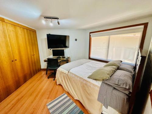 1 dormitorio con 1 cama y escritorio con ordenador en Casa con vista a playa y laguna, en Dichato