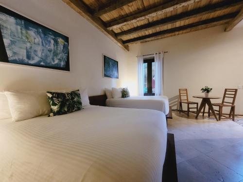 a bedroom with two beds and a table and chairs at LUCA HOTEL Heritage Residences Signature Collection in Santo Domingo